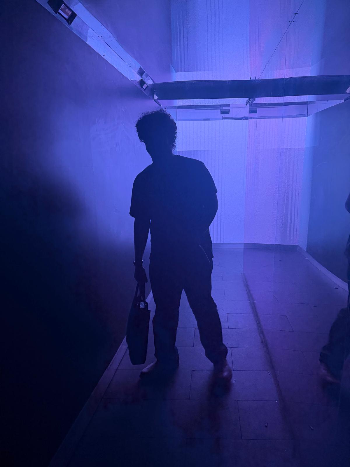Hoodi silhouetted in a blue-lit corridor